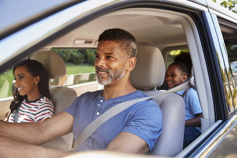 Auto Insurance - View of a Cheerful Family Driving in a Car During a Road Trip