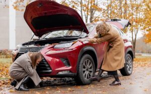 Two women inspecting car on side of road in need of roadside assistance